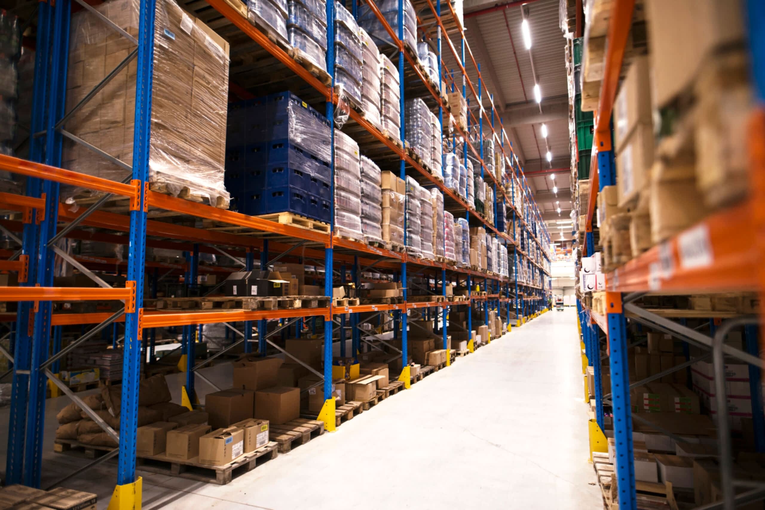 interior-large-distribution-warehouse-with-shelves-stacked-with-palettes-goods-ready-market-scaled